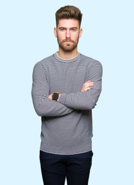 Çapraz kolları olan yüzünde çizgili süveter şüpheci ve sinir, onaylamayan ifade giyen genç yakışıklı adam. Negatif kişi.