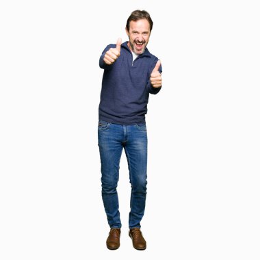 Orta yaş yakışıklı adam el ile olumlu jest yapıyor onayladı bir kazak giymiş, başparmak kadar gülümseyen ve başarı için mutlu. Kamera bakarak, kazanan jest.