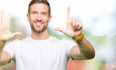 Yakışıklı adam gösterilen ve parmakları ile işaret casual beyaz t-shirt giyen kendinden emin ve mutlu gülümseyerek süre yedi numara.
