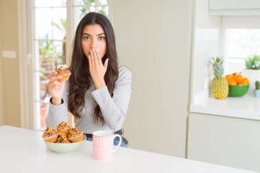 Çikolatalı çörek yiyen ve kahve içen genç kadın, hata için utanç ile şok, korku ifadesi, sessizlikte korkmuş, gizli kavram