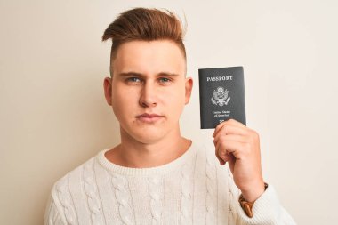 Genç yakışıklı adam ciddi düşünme akıllı yüz üzerinde emin bir ifade ile izole beyaz arka plan üzerinde ABD pasaportu tutan