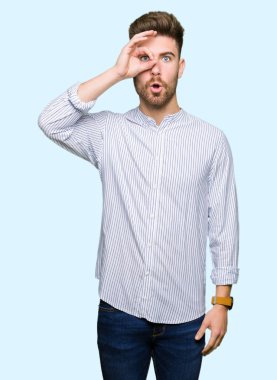 Yakışıklı genç adam şaşırmış yüz ifadesiyle, parmaklarının arasından bakarak iyi bir hareket yapıyor. İnançsız ifade.