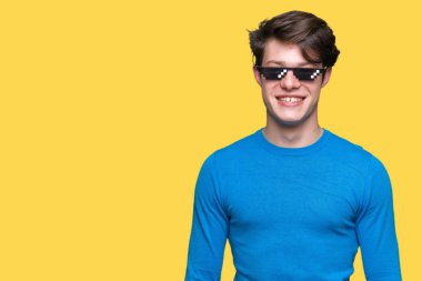 Yüzünde mutlu ve güzel bir gülümseme ile izole arka plan üzerinde komik thug hayat gözlük takan genç adam. Şanslı kişi.