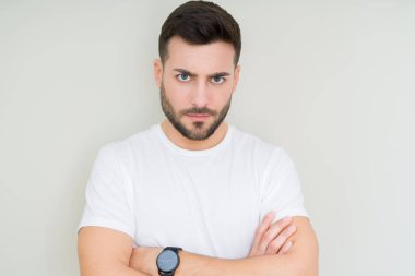 İzole arka plan şüpheci ve sinir, onaylamayan ifade yüz çapraz kolları üzerinde rahat beyaz t-shirt giyen genç yakışıklı adam. Negatif kişi.