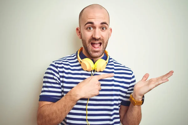 Joven Escuchando Música Con Auriculares Amarillos Sobre Fondo Aislado Asombrado —  Fotos de Stock