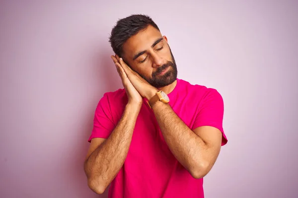 孤立したピンクの背景の上に立つTシャツを着た若いインド人男性は 目を閉じて微笑みながら 夢を見て 手をつないで一緒にポーズをとる疲れた眠り — ストック写真