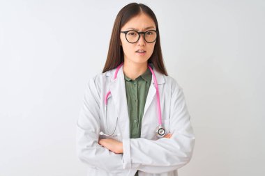 İzole beyaz arka plan üzerinde gözlük stetoskop giyen genç Çinli keşfetmek kadın şüpheci ve sinir, kesişen kollar ile yüz üzerinde ifade onaylamıyor. Negatif kişi.