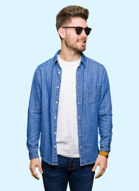 Denim ceket uzak tarafına gülümseme ile yüzünde, doğal ifade arıyorum giyen genç yakışıklı zarif adam. Kendine güvenen gülüyor.