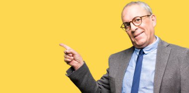 Yakışıklı üst düzey businesss gözlük adam ve kameraya bakarak yan el ve parmak ile işaret yüzünde kocaman bir gülümseme ile kravat.