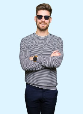 Genç yakışıklı gülen surat ile gülümseyerek kameraya seyir silah çapraz giyen güneş gözlüğü adam. Olumlu bir kişi.