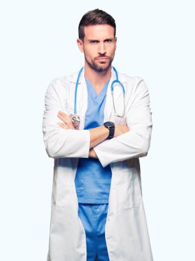 Yakışıklı Doktor izole arka plan şüpheci ve sinir, onaylamayan ifade yüz çapraz kolları üzerinde tıbbi üniforma giyen adam. Negatif kişi.
