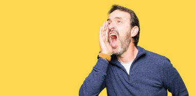 Orta yaş yakışıklı adam bağırıyor ve ağzı üzerinde el ile yan için çığlık bir kazak giyiyor. İletişim kavramı.