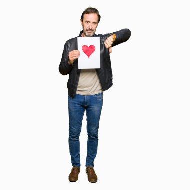 Başparmak aşağı, ret kavramı ile eksi işareti gösterilen yakışıklı orta yaş erkek holding kağıt kızgın yüzü ile kırmızı kalpli sevmemek