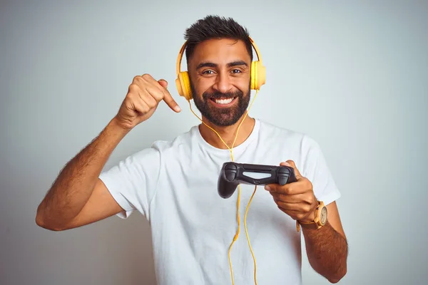 孤立した白い背景の上にヘッドフォンを使用してビデオゲームをプレイするアラブのインドのゲーマーの男は 手と指で非常に幸せなポインティング — ストック写真
