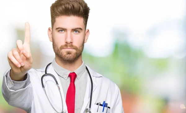Νεαρός Γιατρός Όμορφος Άνθρωπος Φορώντας Ιατρική Παλτό Κατάδειξης Δάχτυλο Επάνω — Φωτογραφία Αρχείου