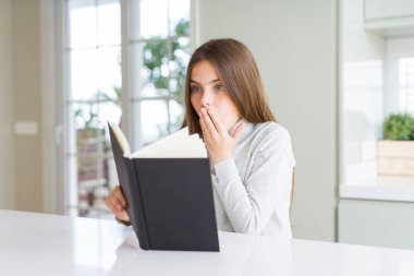 Evde bir kitap okuma güzel genç kız el ile hata için utanç ile şok, korku ifade, sessizlik korkuyor, gizli kavramı ile ağız kapağı