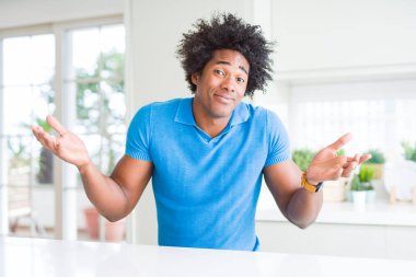 Afrikalı-Amerikalı adam evde clueless ve şaşkın bir ifadeyle kollar ve eller kaldırdı. Şüphe kavramı.