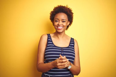 Beauitul Afrikalı Amerikan kadın birlikte el ile izole sarı arka plan üzerinde yaz t-shirt giyiyor ve parmaklar rahat ve neşeli gülümseyen geçti. Başarı ve iyimserlik