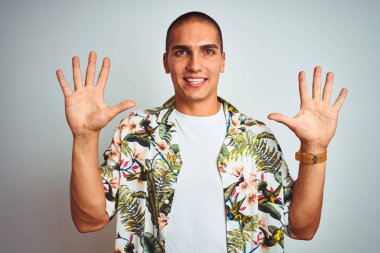 Beyaz arka planda gösteren ve parmaklar sayısı on ile işaret yukarı üzerinde Hawaii gömlek giyen tatil genç yakışıklı adam emin ve mutlu gülümseyen.