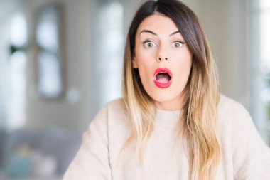 Evde korkuyor ve şok sürpriz ifade, korku ve heyecan yüz ile kış kazak giyen genç güzel kadın.