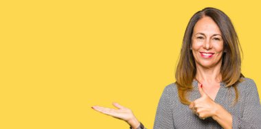 Mutlu ve neşeli gülümseyen güzel orta yaş iş kadın gösteren palm el ve iş tamam jestle başparmak yukarıya,