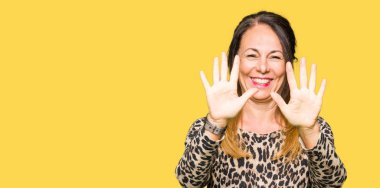 Güzel orta yaş kadın leopar hayvan baskı elbise gösteren ve parmak sayısı on ile işaret kadar kendine güvenen ve mutlu gülümseyen giyen.