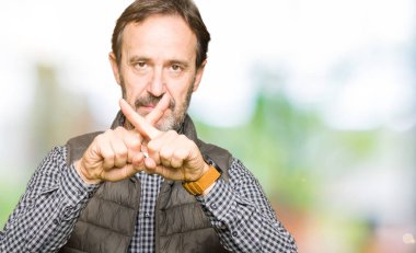 Orta yaş yakışıklı adam giyen kış yelek ret ifade geçiş parmakları eksi işareti yapıyor