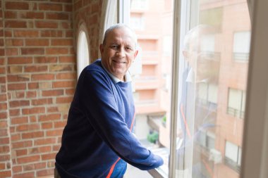 Gelecek için bakan pencerenin yanında, neşeli, mutlu ve olumlu gülümseyen yakışıklı orta yaş üst düzey adam