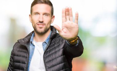 Elin avuç durağı şarkı yapıyor kış ceket giyen yakışıklı adam. Negatif ve ciddi bir jest yüz ifadesiyle uyarı.