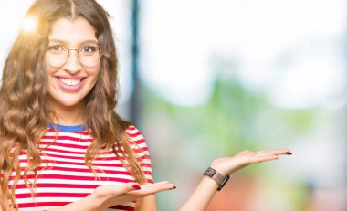 Giyen genç güzel kadın işaretçi el ve avuç, yanında reklam mutlu ve kendinden emin gülümseyen sunulması gözlük