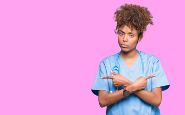 Genç Afro-Amerikan doktor kadın izole arka plan üzerinde işaretleme için her iki parmak, farklı yönde ile katılmıyorum
