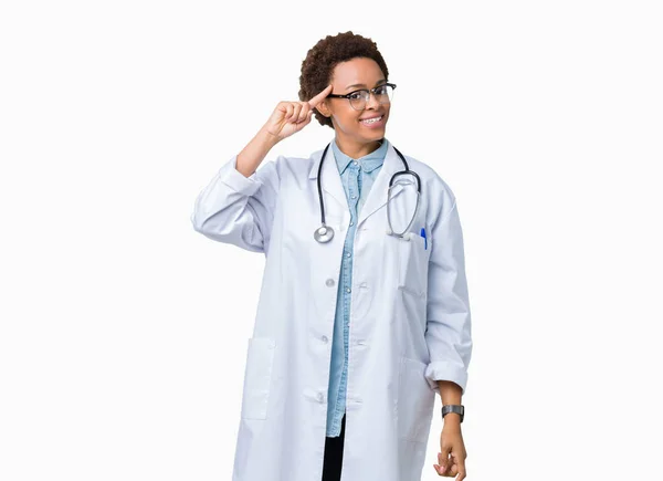 1本の指で頭を指さしている孤立した背景の上に医療コートを着た若いアフリカ系アメリカ人の医者の女性 偉大なアイデアや思考 良い記憶 — ストック写真