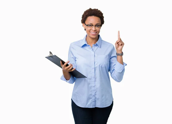 幸せそうな顔 ナンバーワンのアイデアや質問ポインティング指で孤立した背景にクリップボードを保持している若いアフリカ系アメリカ人ビジネス女性を驚かせた — ストック写真