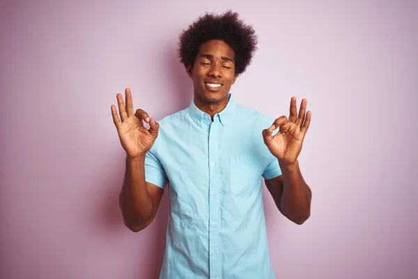 年轻的美国男子 一个非洲的头发 穿着蓝色衬衫站在孤立的粉红色背景放松和微笑与眼睛闭着手指做冥想手势 瑜伽概念 — 图库照片