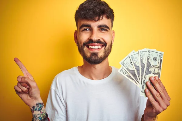 Young Man Tattoo Holding Dollars Standing Isolated Yellow Background Very — Stock Photo, Image