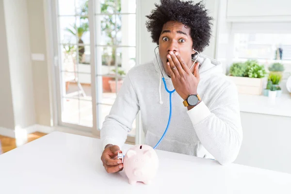 저금통 재정적 건강을 확인하는 청진기를 아프리카계 미국인 남성이 두려움의 개념에 — 스톡 사진