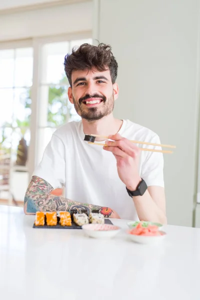 Young man eating sushi asian food using choopsticks