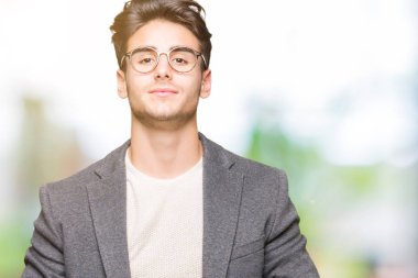 Arka plan eller birlikte üzerinde gözlük takan genç iş adamı izole ve rahat ve neşeli gülümseyen parmak çarpı işareti. Başarı ve iyimser