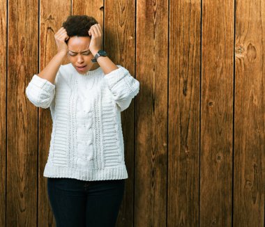 Çünkü çaresiz ve stresli baş ağrısı acı izole arka plan üzerinde kazak giyen güzel genç Afro-Amerikan kadın ağrı ve migren. Ellerini kafasına.