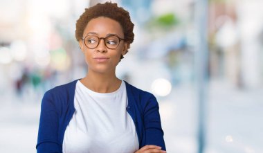 Genç güzel Afrikalı-Amerikalı kadın görünümlü yan ve dik dik bakma uzağa düşünce gülümseyen izole arka plan üzerinde gözlük.