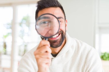 Yakışıklı adam büyüteç kullanarak, komik yüzler yapıyor