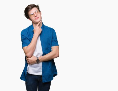 Çene düşünme hakkında soru, dalgın ifade üzerine el ile izole arka plan üzerinde gözlük takan yakışıklı delikanlı. Düşünceli yüzüyle gülümsüyor. Şüphe kavramı.