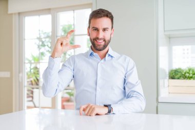 Yakışıklı iş adamı gülümseyen ve kendinden emin bir şekilde el iyle gesturing yaparken parmaklarıyla işaret ve kamera. Ölçü kavramı.
