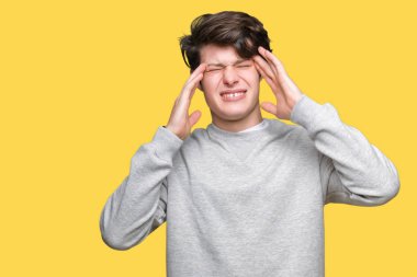 Genç yakışıklı sportif adam kazak giyiyor çünkü umutsuz ve stresli baş ağrısı acı izole arka plan üzerinde ağrı ve Migren. Ellerini kafasına.