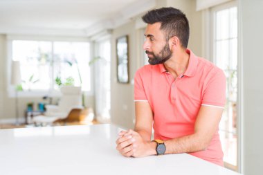 Evde yan arayan rahat t-shirt giyen yakışıklı İspanyol adam, güvenli bir gülümseme ile doğal yüzü ile profil poz rahatlayın.