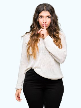 Dudaklarında parmak ile sessiz olmanı beyaz kazak giyen genç güzel kadın. Sessizlik ve gizli kavramı.