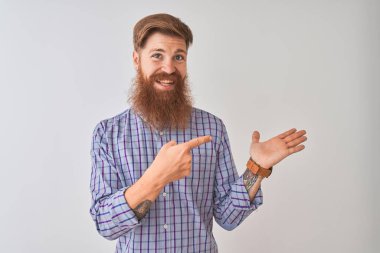 Genç Redhead İrlandalı adam rahat gömlek üzerinde ayakta izole beyaz arka plan hayran ve kamera için gülümseyen el ile sunmak ve parmak ile işaret.