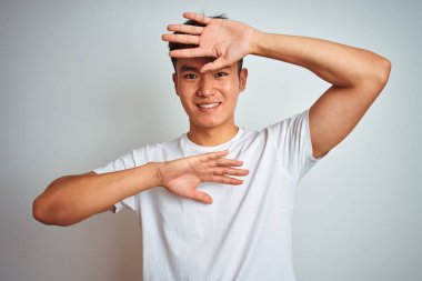 Genç Asya Chinese adam giyen t-shirt ayakta üzerinde izole beyaz arka plan gülümseyen neşeli oyun Peek bir Boo ile eller gösteren yüz. Sürpriz ve çıkıldı