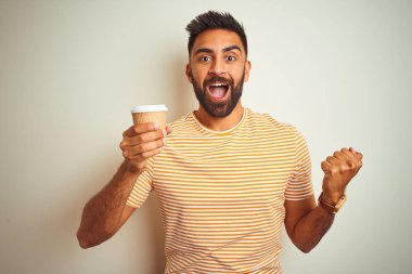 Genç Hint adam kahve içme fincan izole beyaz arka plan üzerinde ayakta gurur çığlık ve zafer kutluyor ve başarı çok heyecanlı, tezahürat duygu