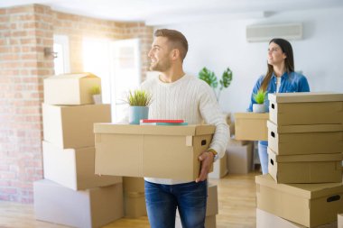 Genç çift yeni bir ev, yeni bir dairede mutlu tutan karton kutular gülümseyen hareket